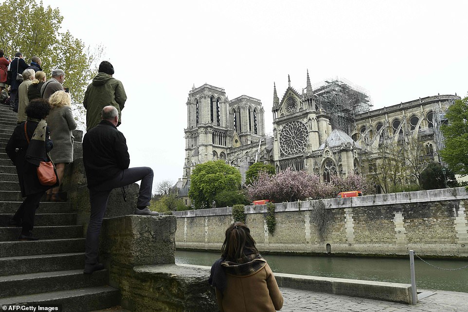 12331148-6926257-Onlookers_stand_on_the_banks_of_the_Seine_river_as_the_nation_wa-a-78_1555397880900